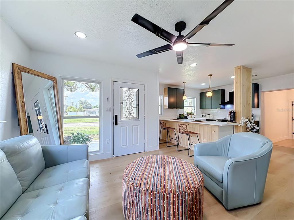 A living room with light blue furniture, a patterned ottoman, and an open-concept kitchen — 415 MERCADO AVENUE, ORLANDO, FL
