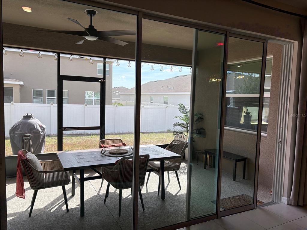 A covered patio with a dining set, ceiling fan, and screen enclosure overlooks a backyard — 5870 SW 80TH PLACE, OCALA, FL