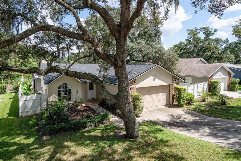 An exterior view of a single-story house with a garage, driveway, and a large tree — 116 QUAIL RIDGE COURT, SANFORD, FL