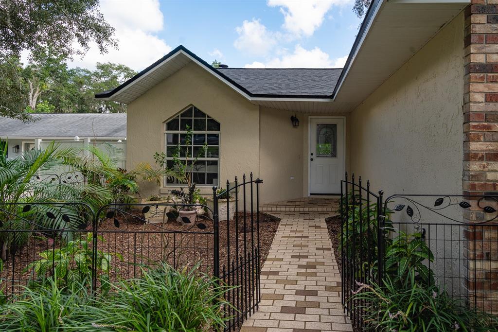 A brick walkway leads to the front entrance of a house with a pointed window — 116 QUAIL RIDGE COURT, SANFORD, FL