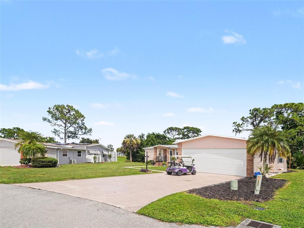 A view of two single-story houses with a concrete driveway and a purple golf cart — 19808 FRENCHMANS COURT, NORTH FORT MYERS, FL