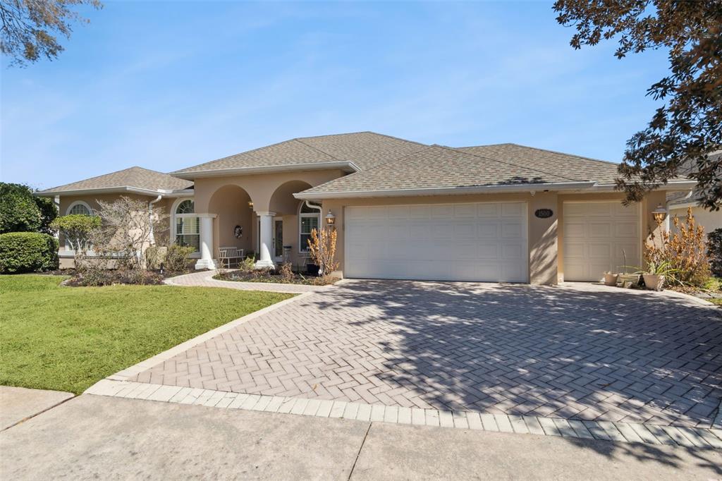 A single-story house with a beige stucco exterior, a three-car garage, and a paved driveway — 1500 EDGEWATER DRIVE, MOUNT DORA, FL