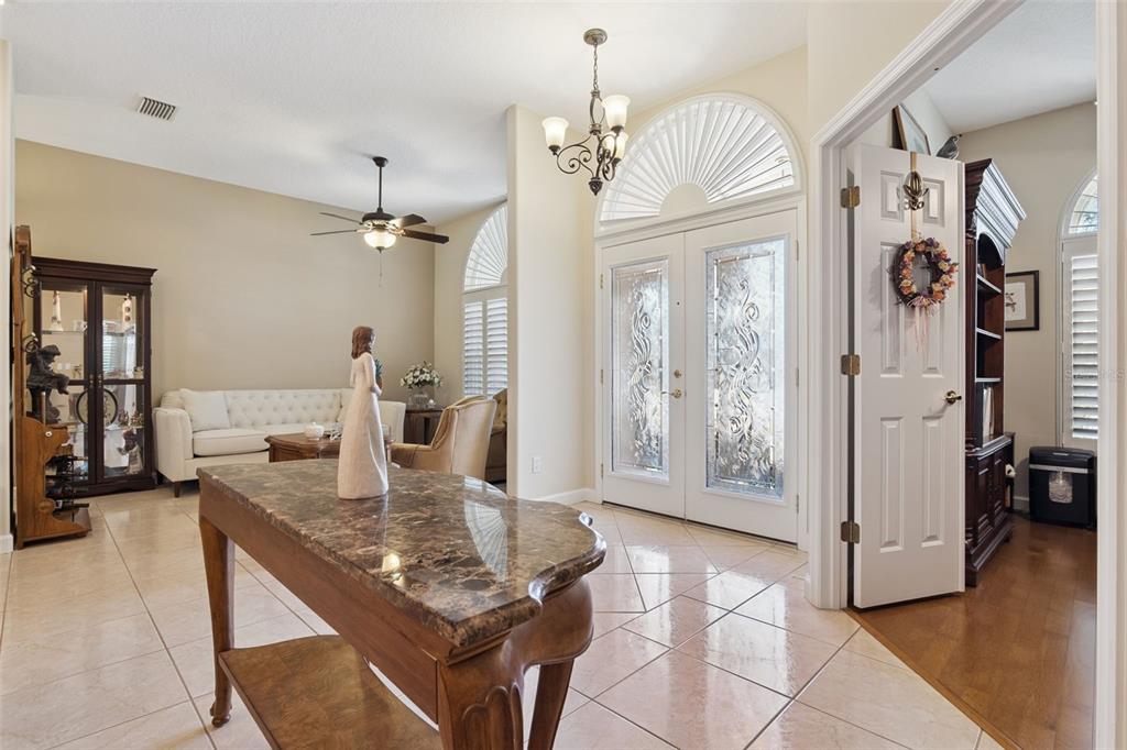 A dining and living area features tile floors, wooden furniture, and a chandelier — 1500 EDGEWATER DRIVE, MOUNT DORA, FL