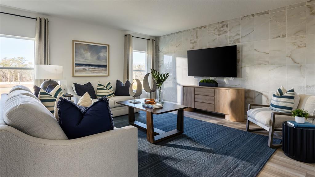 A living room features a marble-tiled accent wall, a large television, and a blue rug — 9255 ORCHARD PARK LANE, DADE CITY, FL