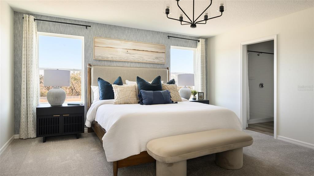 A bedroom features a bed with blue and beige pillows, a bench, and two windows — 9255 ORCHARD PARK LANE, DADE CITY, FL