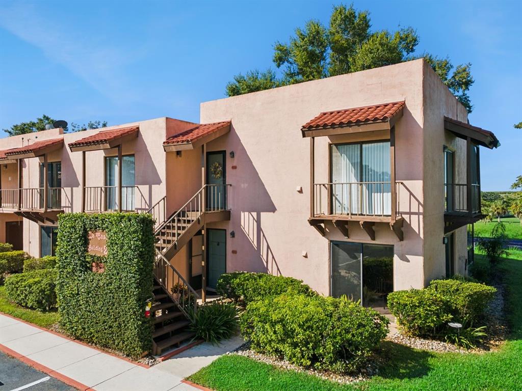 A two-story stucco apartment building with exterior stairs, balconies, and a tiled roof — 109 LA CASA UNIT 109, LAKE WALES, FL