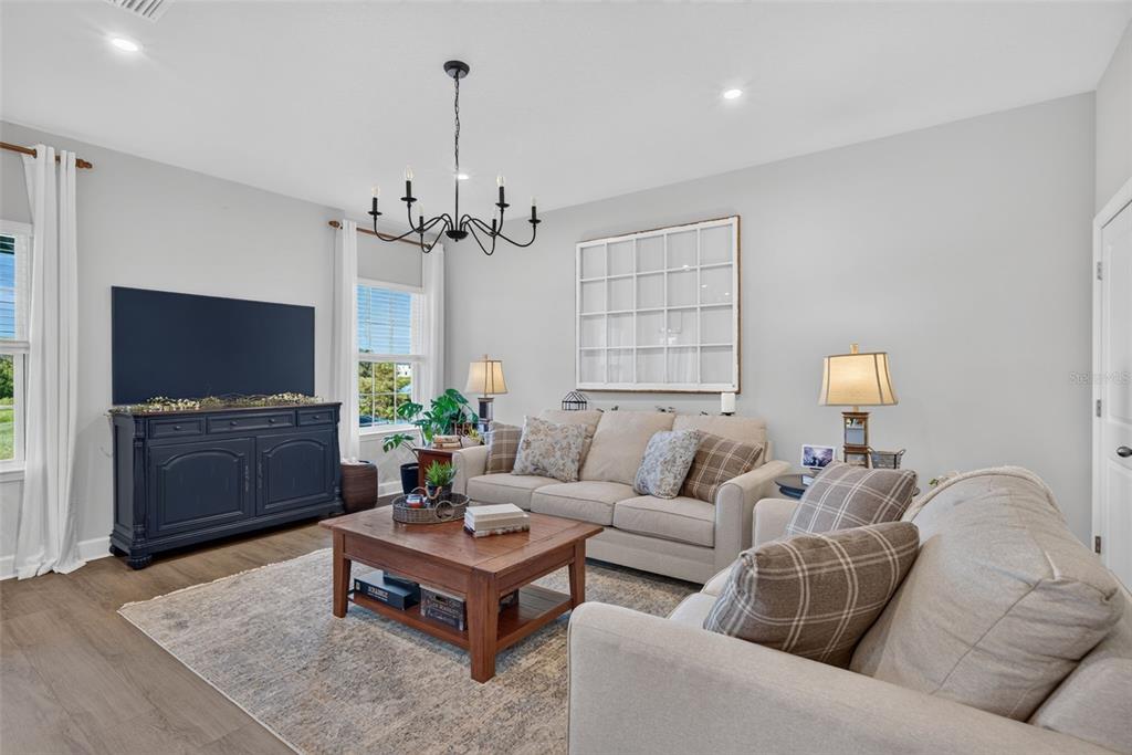 A living room features a beige sofa, a wooden coffee table, and a dark media console — 14076 CRIMSON AVENUE, LAKEWOOD RANCH, FL
