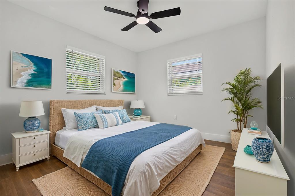 A bedroom features a wicker bed frame, blue accents, two windows, and a ceiling fan — 7037 69TH STREET N, PINELLAS PARK, FL