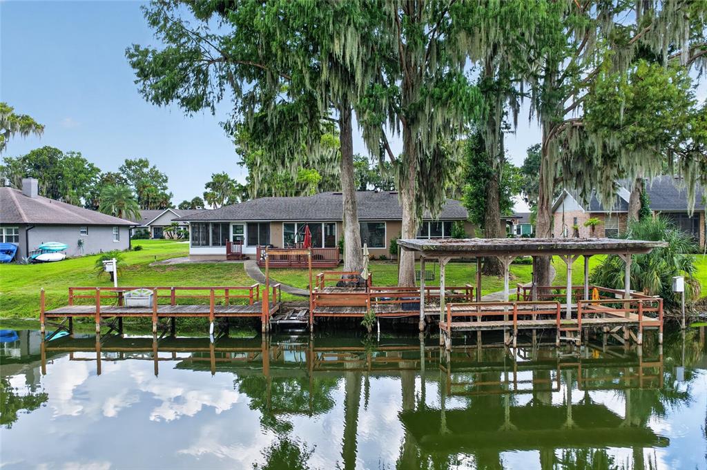 A waterfront house with a wooden dock and boat slip under large mossy trees — 235 TEMPLE CIRCLE, EUSTIS, FL
