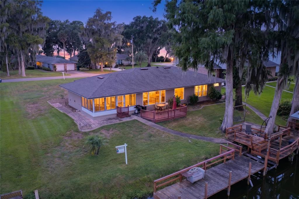 An aerial view of a single-story house with a wooden deck and dock on water — 235 TEMPLE CIRCLE, EUSTIS, FL
