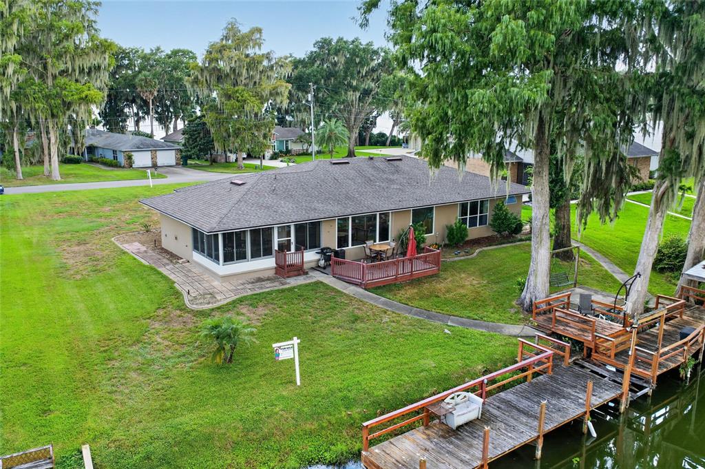 An aerial view of a single-story house with a wooden deck and dock on water — 235 TEMPLE CIRCLE, EUSTIS, FL