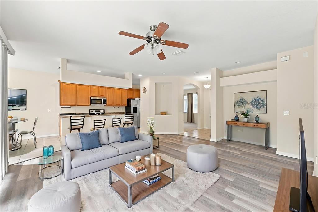 An open-concept living room and kitchen featuring wood-look flooring, a ceiling fan, and neutral walls — 4469 STONEY RIVER DRIVE, MULBERRY, FL
