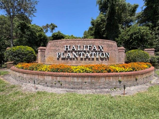 A brick entrance sign for Halifax Plantation sits behind a bed of colorful flowers — 3513 KILGALLEN COURT, ORMOND BEACH, FL