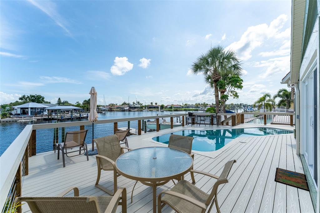 A waterfront deck features a swimming pool, patio furniture, and a view of the canal — 835 SYMPHONY ISLES BOULEVARD, APOLLO BEACH, FL