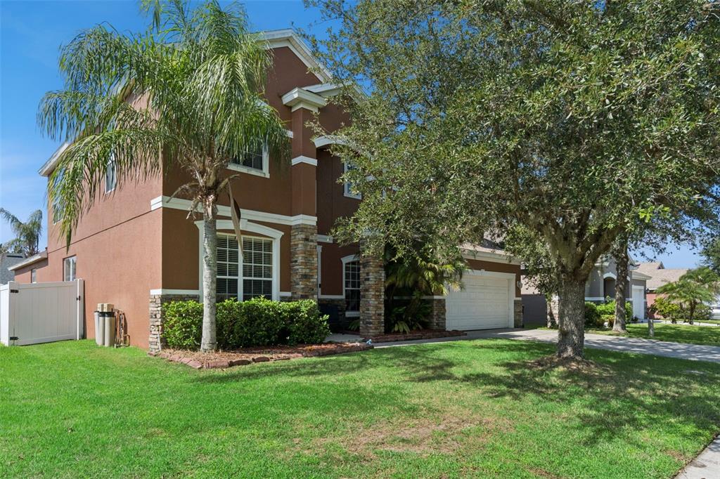A two-story house with brown stucco, stone accents, a palm tree, and a front lawn — 351 MICHIGAN ESTATES CIRCLE, ST CLOUD, FL