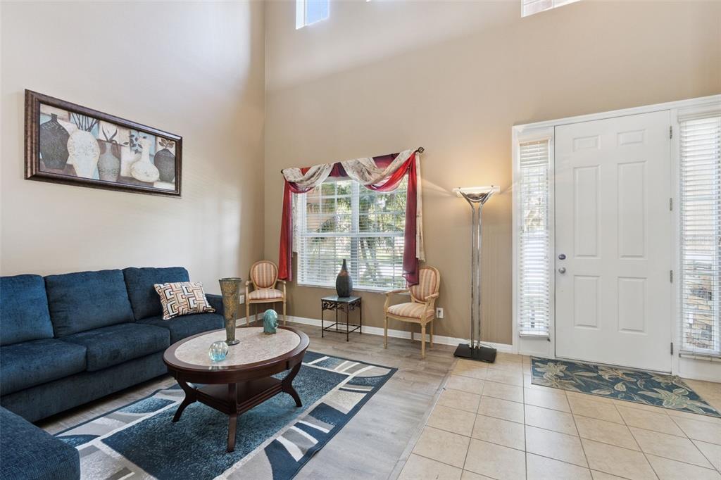 A living room features a blue sofa, a coffee table, two chairs, and high ceilings — 351 MICHIGAN ESTATES CIRCLE, ST CLOUD, FL