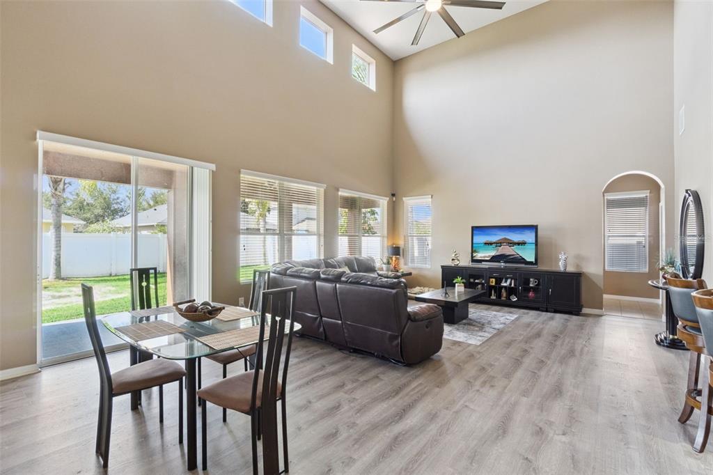 A living and dining area with high ceilings, wood-look flooring, and a glass dining table — 351 MICHIGAN ESTATES CIRCLE, ST CLOUD, FL