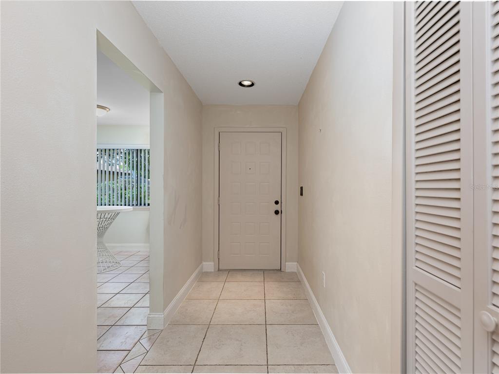 A bright bedroom features light tile flooring, white walls, a crystal light fixture, and windows — 109 WATERWOOD DRIVE, YALAHA, FL