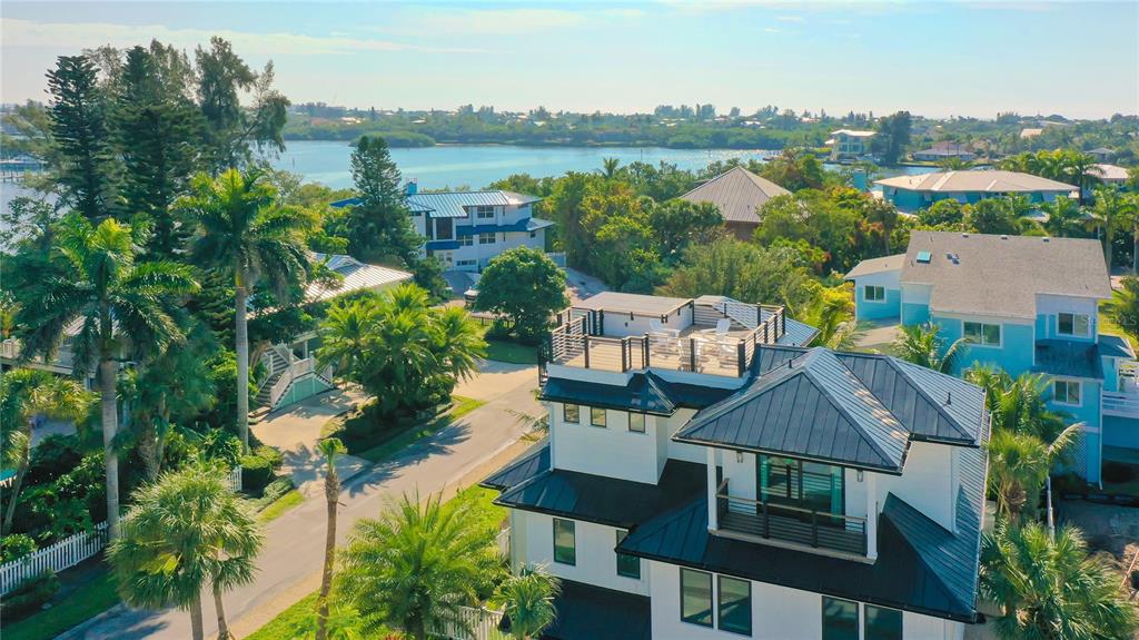 An aerial view shows a modern white house with a rooftop deck near a bay — 307 62ND STREET, HOLMES BEACH, FL