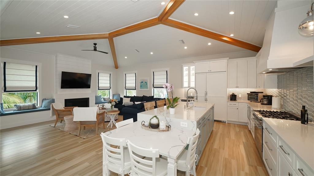 An open-concept kitchen and living area features vaulted ceilings with wood beams and white cabinetry — 307 62ND STREET, HOLMES BEACH, FL