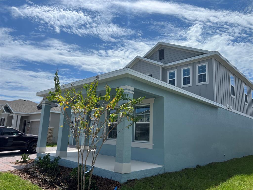A light blue two-story house features a covered front porch and gray vertical siding — 5590 FIONA LANE, ST CLOUD, FL
