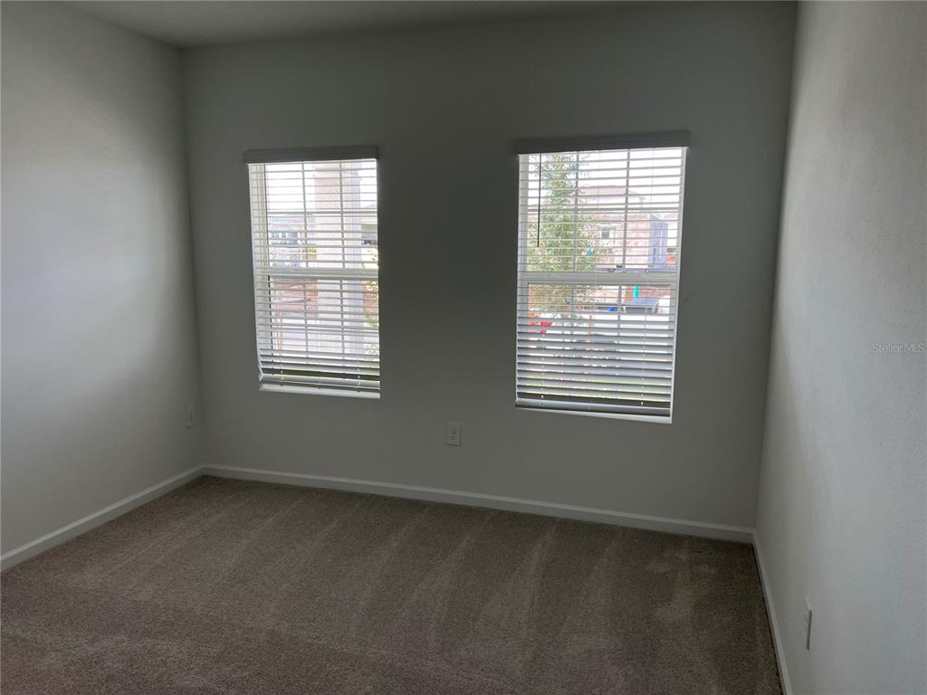 An empty bedroom features beige carpeting, light gray walls, and two windows with white blinds — 5590 FIONA LANE, ST CLOUD, FL