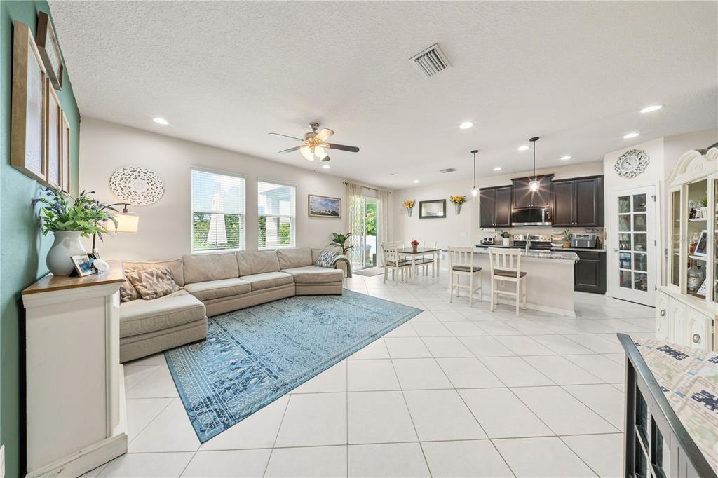 An open-concept living room and kitchen featuring tile floors, a sectional sofa, and dark cabinetry — 3123 MELA COURT, HOLIDAY, FL