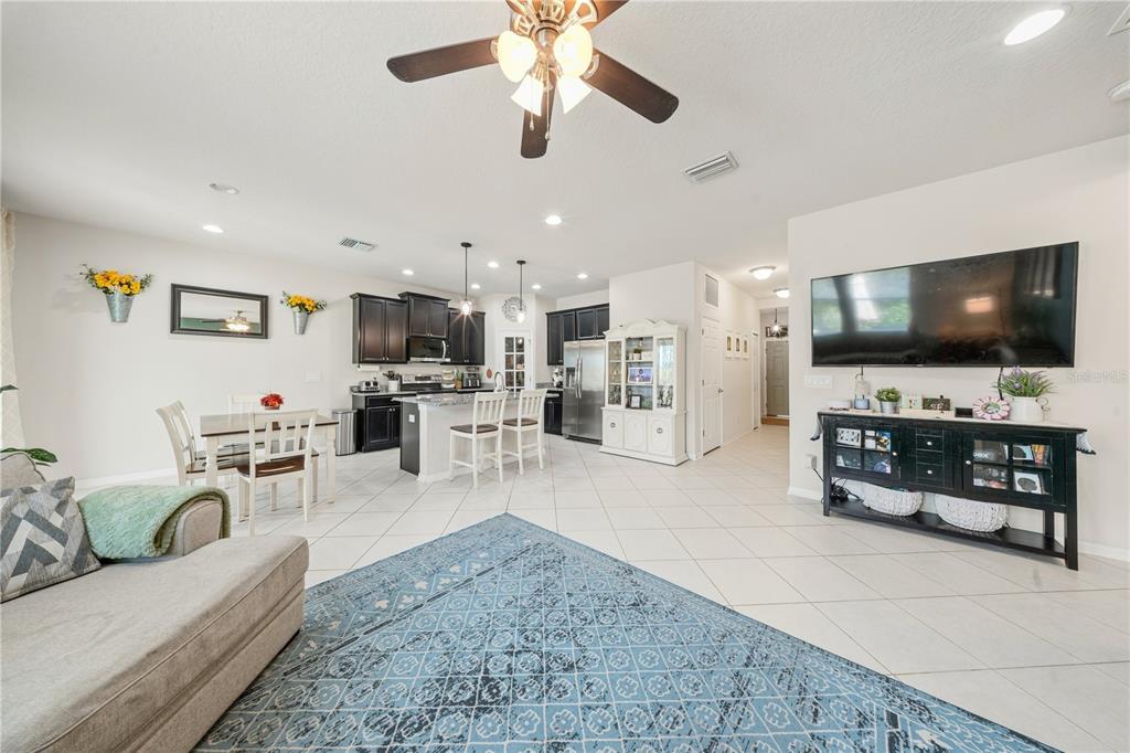 An open-concept living room and kitchen featuring tile floors, dark cabinetry, and a ceiling fan — 3123 MELA COURT, HOLIDAY, FL