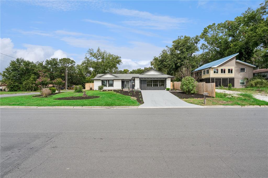 A single-story house with a white and gray exterior sits behind a concrete driveway — 1500 WEST AVENUE, CLERMONT, FL