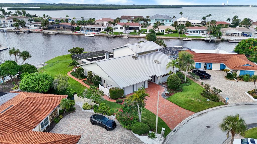 An aerial view shows a waterfront house with a metal roof and brick driveway — 5060 PORPOISE PLACE, NEW PORT RICHEY, FL