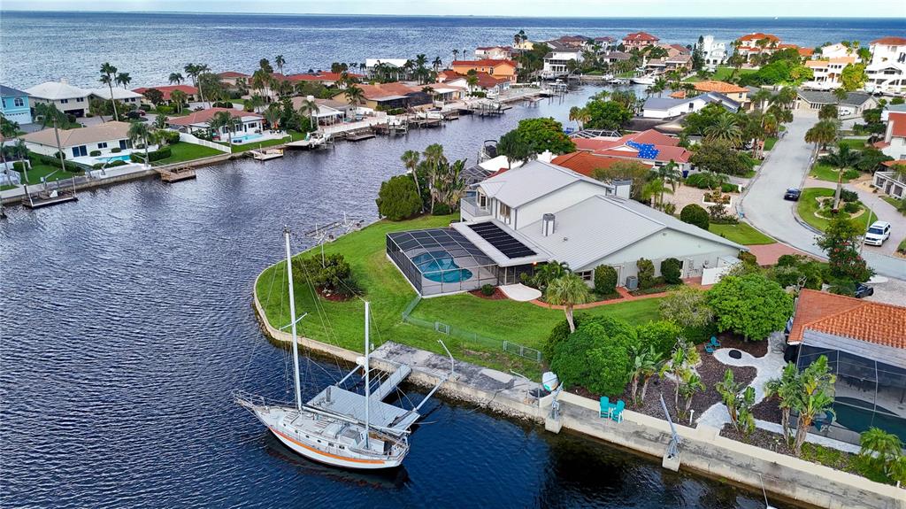 An aerial view shows a waterfront house with a pool, dock, and sailboat — 5060 PORPOISE PLACE, NEW PORT RICHEY, FL