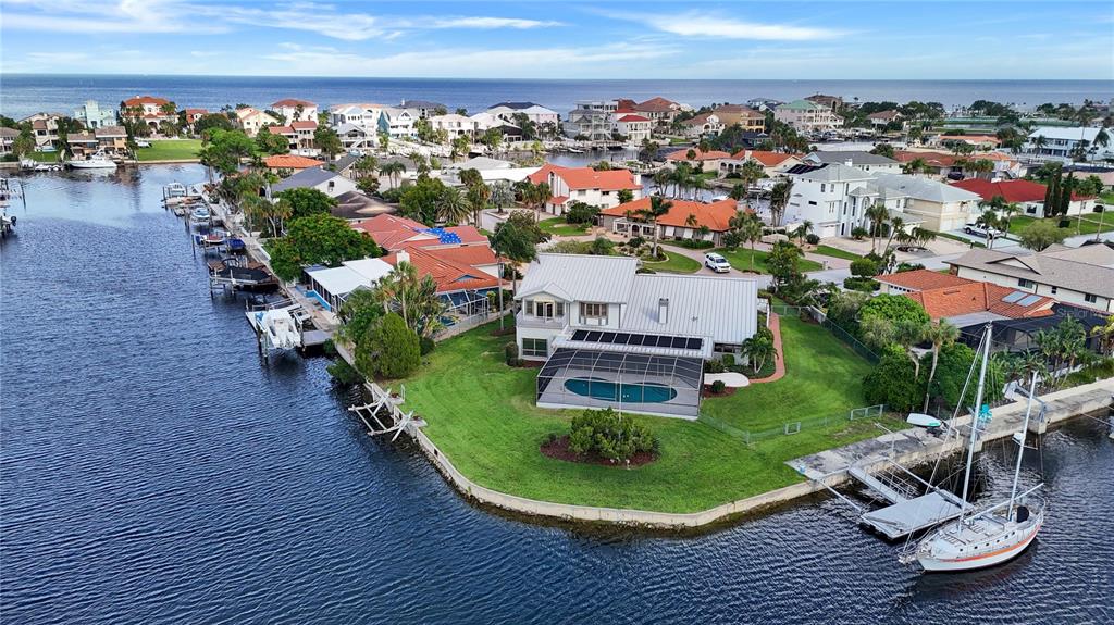 An aerial view shows a waterfront house with a pool, dock, and sailboat on a canal — 5060 PORPOISE PLACE, NEW PORT RICHEY, FL