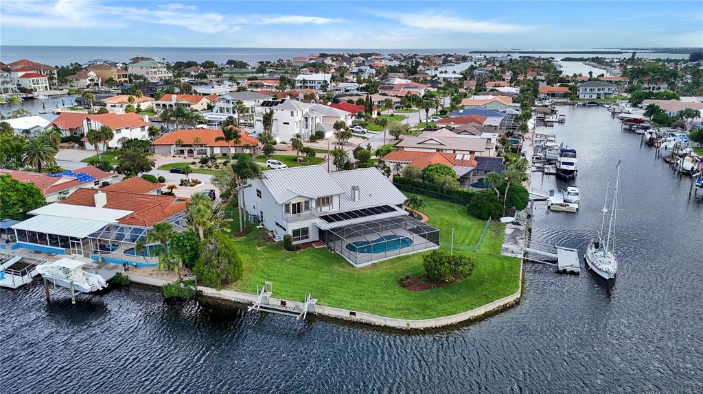 An aerial view shows a waterfront house with a pool enclosure and private boat dock — 5060 PORPOISE PLACE, NEW PORT RICHEY, FL