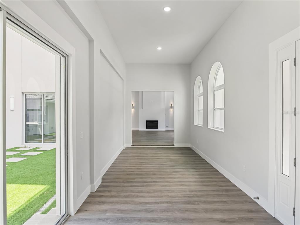 A living room features light-colored walls, wood-look flooring, a stone fireplace, and a glass door — 1190 W LAKESHORE DRIVE, CLERMONT, FL
