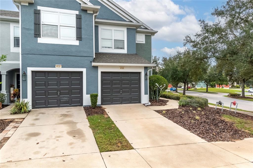 A two-story townhouse exterior features two dark gray garage doors and concrete driveways — 4122 SW 54TH CIRCLE, OCALA, FL