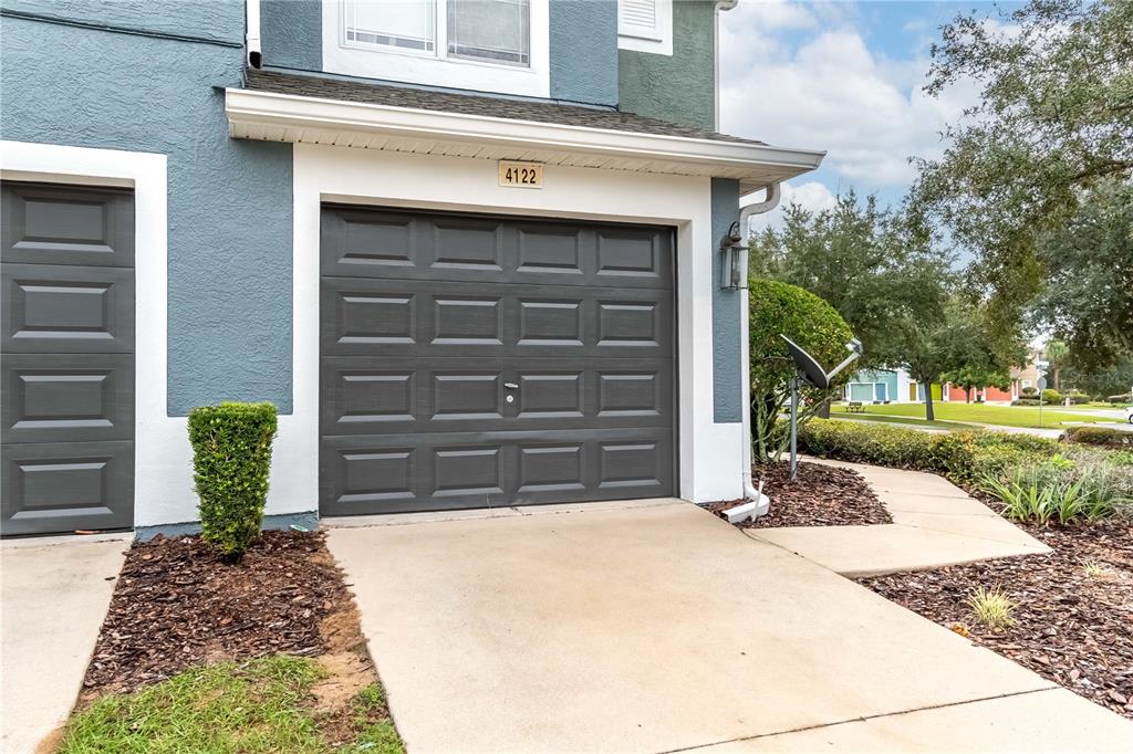 A gray garage door with a house number above it sits next to a walkway — 4122 SW 54TH CIRCLE, OCALA, FL