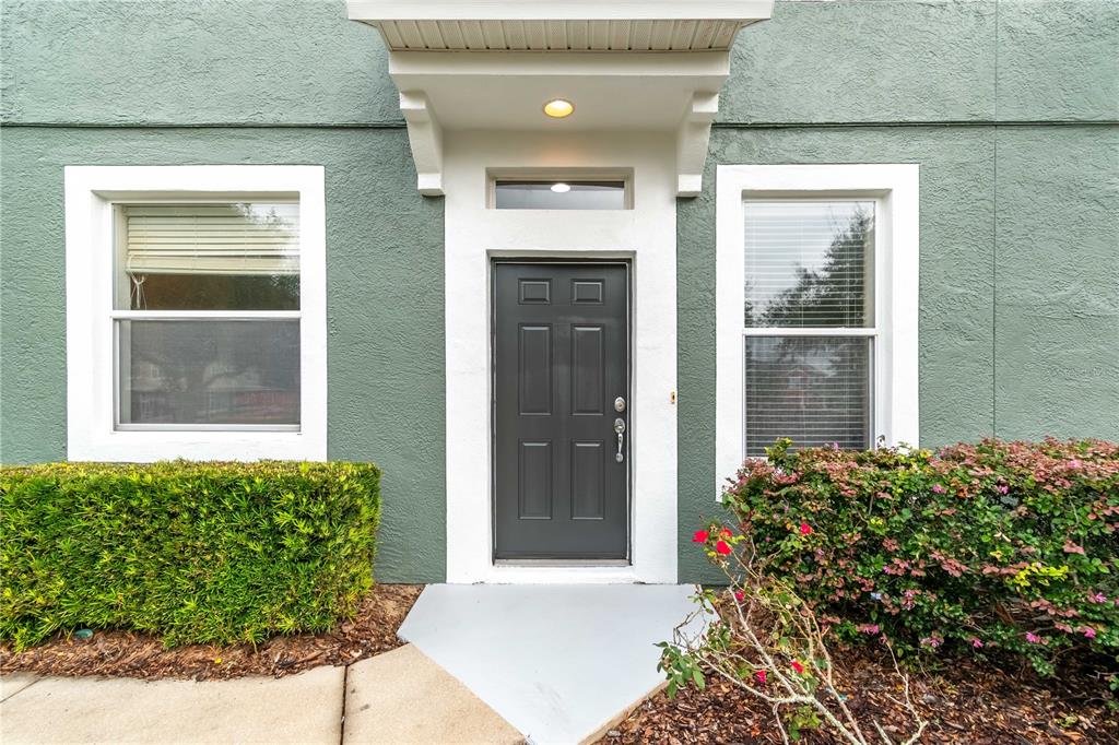 The exterior of a home features a dark gray door, white trim, and green siding — 4122 SW 54TH CIRCLE, OCALA, FL