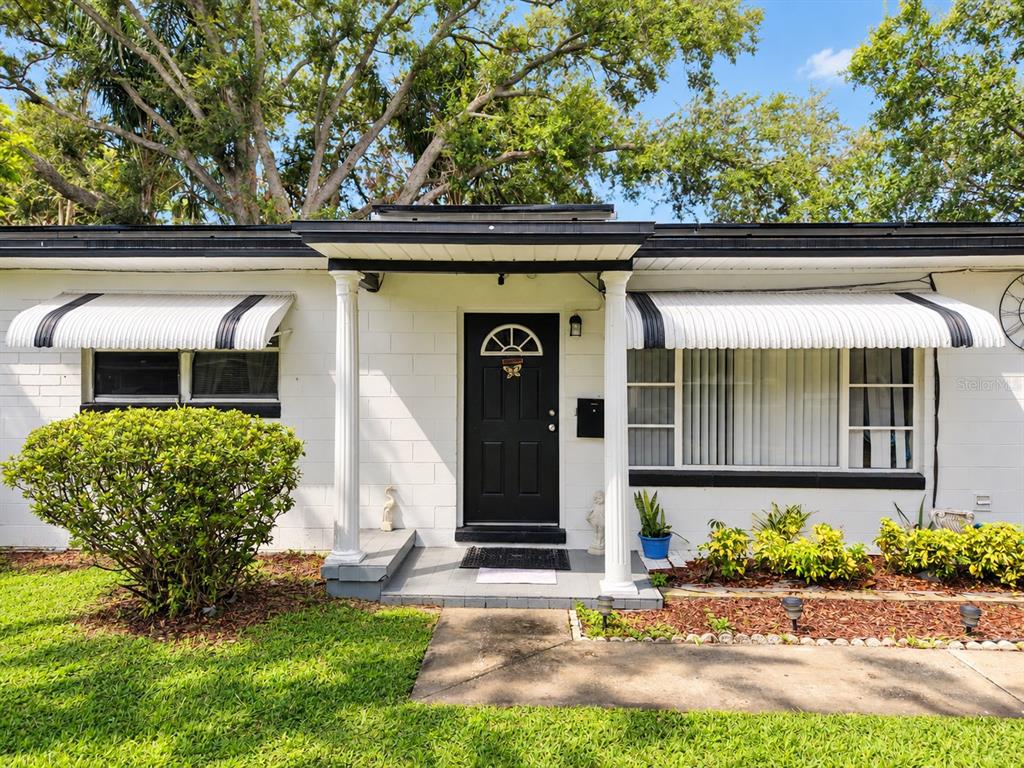 The exterior of a white concrete block house features a black front door and awnings — 708 SANTA FE LANE, ORLANDO, FL