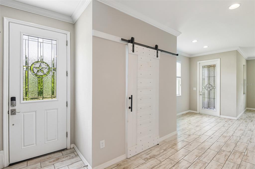 A bright, open-concept living area features wood-look tile flooring, a ceiling fan, and a kitchen — 6706 ROCKY PARK STREET, TAMPA, FL