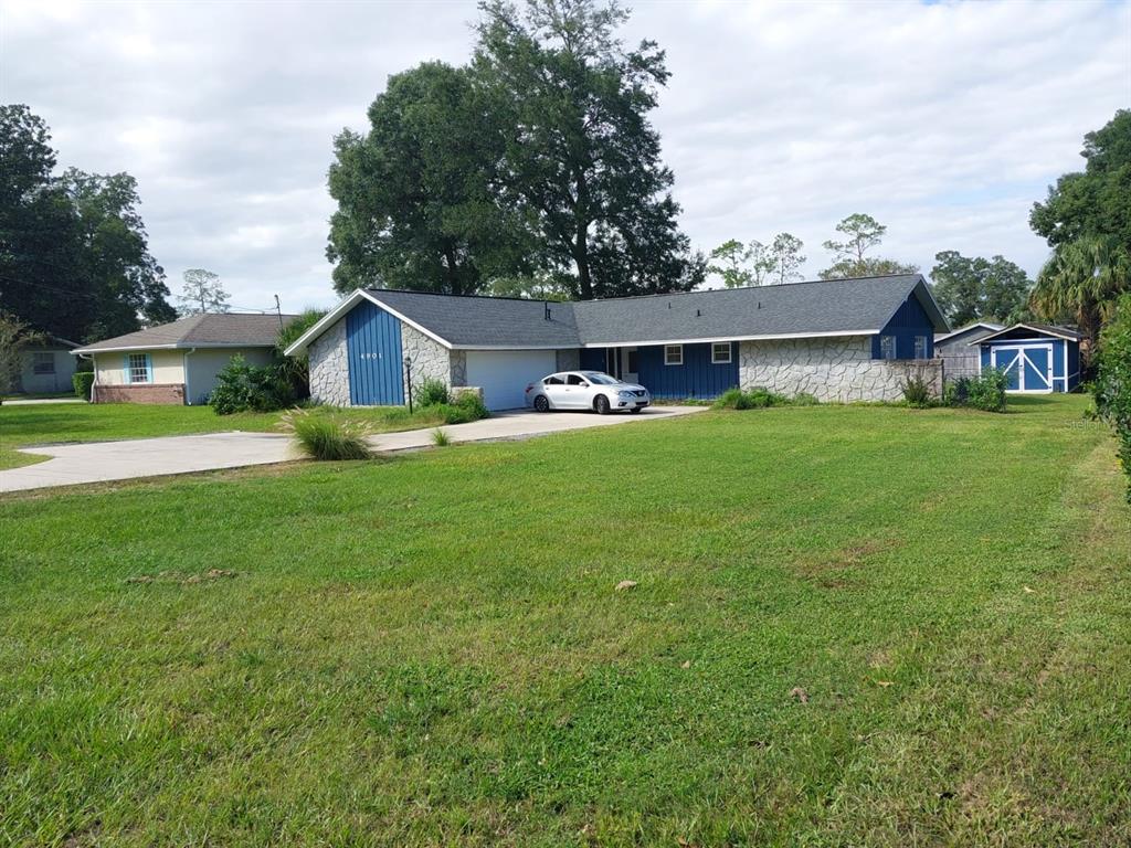 A single-story house with blue vertical siding and stone accents sits on a grassy lot — 4901 NE 7TH STREET, OCALA, FL
