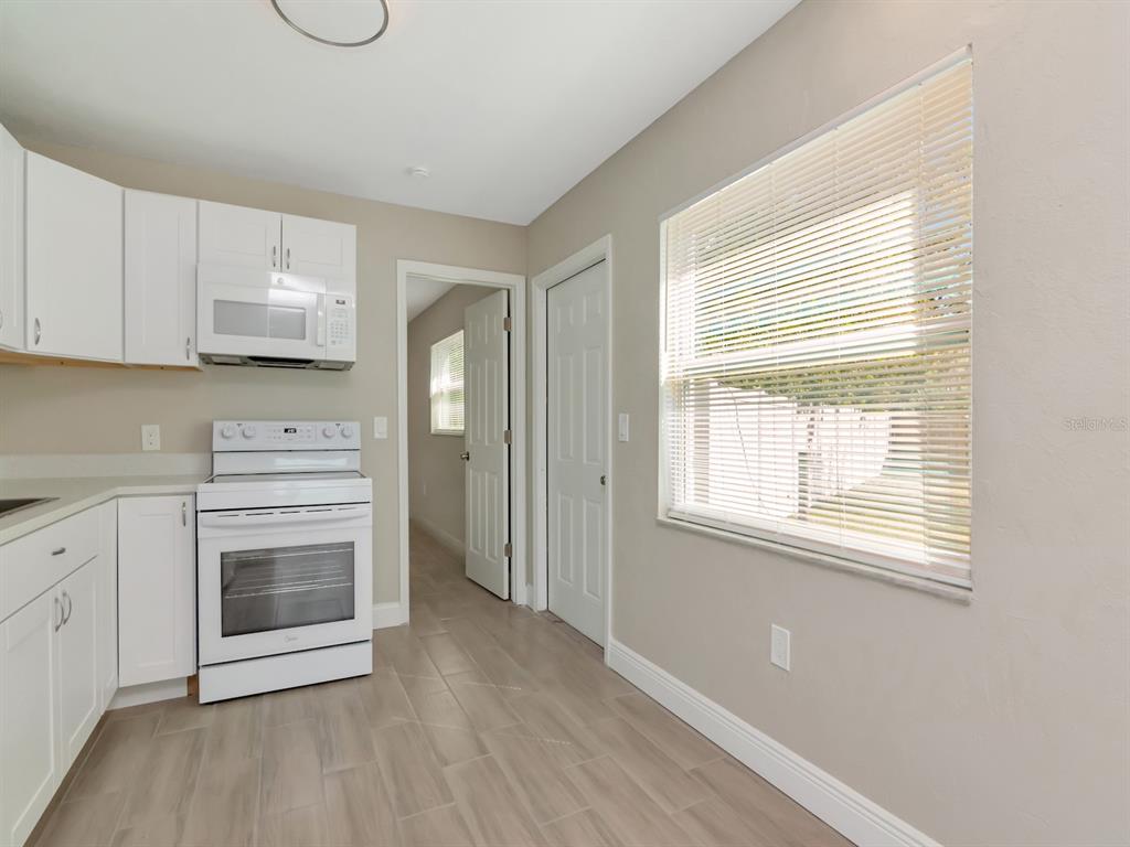 A kitchen features white cabinets, a white stove, and light wood-look flooring — 1207 62ND AVENUE E, BRADENTON, FL