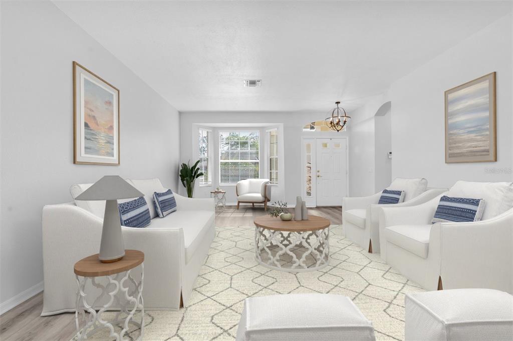 A bright living room features white sofas, a patterned rug, and a central coffee table — 11429 HIDDEN COVE CT., TRINITY, FL