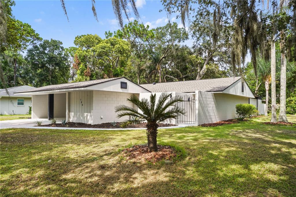 A single-story house with a concrete block exterior, a metal gate, and a palm tree — 580 DEVONSHIRE BOULEVARD, LONGWOOD, FL