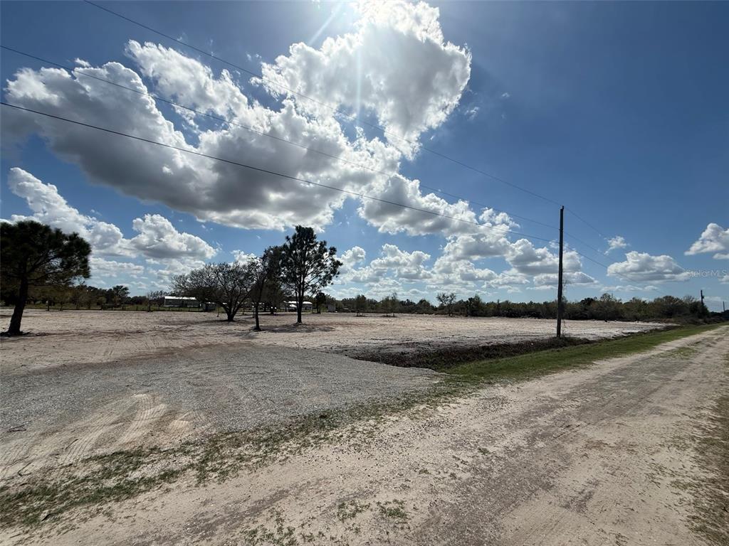 A large, cleared, sandy lot with scattered trees under a bright, cloudy sky — 14416 NW 252ND STREET, OKEECHOBEE, FL