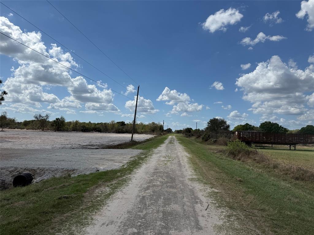 A dirt road stretches through a rural landscape under a blue sky with scattered clouds — 14416 NW 252ND STREET, OKEECHOBEE, FL