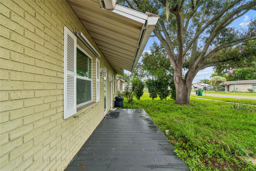 A side view of a house with a painted brick exterior and a wooden deck — 38621 NORTH AVENUE, ZEPHYRHILLS, FL
