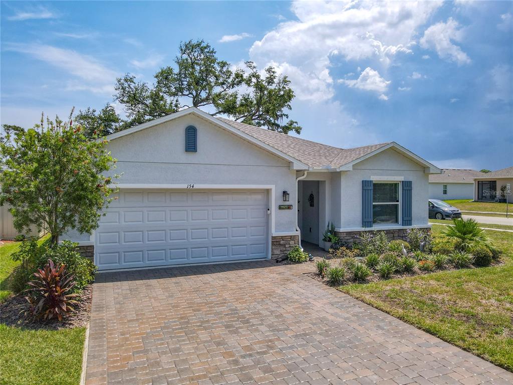 A single-story house with a paved driveway, a two-car garage, and a stone-accented facade — 154 JONES FISH CAMP ROAD, EDGEWATER, FL