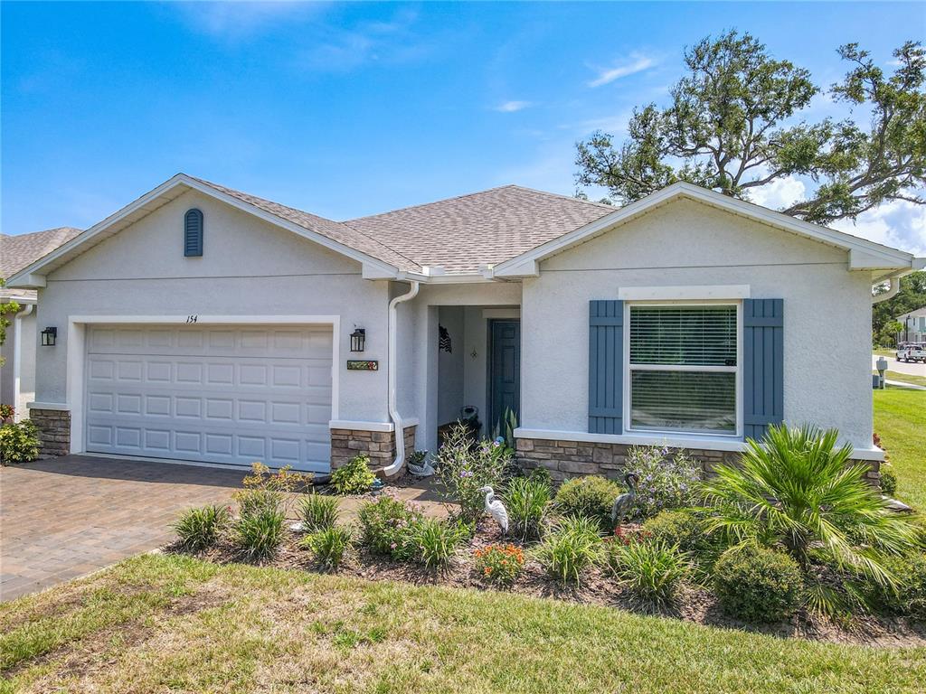 A single-story house with a two-car garage, stone accents, and blue shutters — 154 JONES FISH CAMP ROAD, EDGEWATER, FL