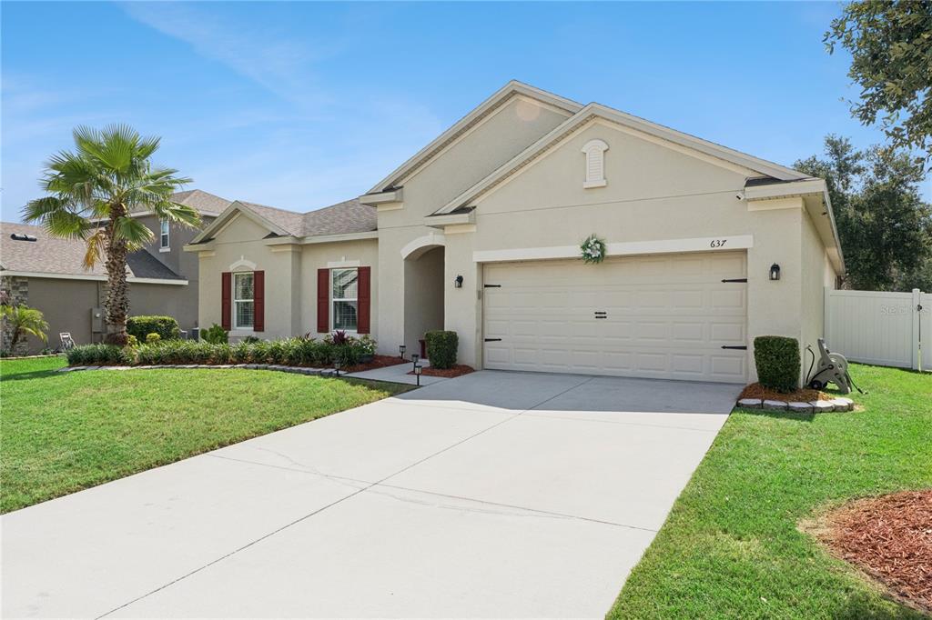 A single-story house with a beige stucco exterior, a two-car garage, and a palm tree — 637 BAY BRIDGE CIRCLE, APOPKA, FL