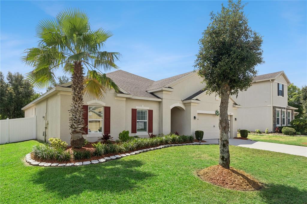A single-story house with a palm tree, manicured landscaping, and a two-car garage — 637 BAY BRIDGE CIRCLE, APOPKA, FL
